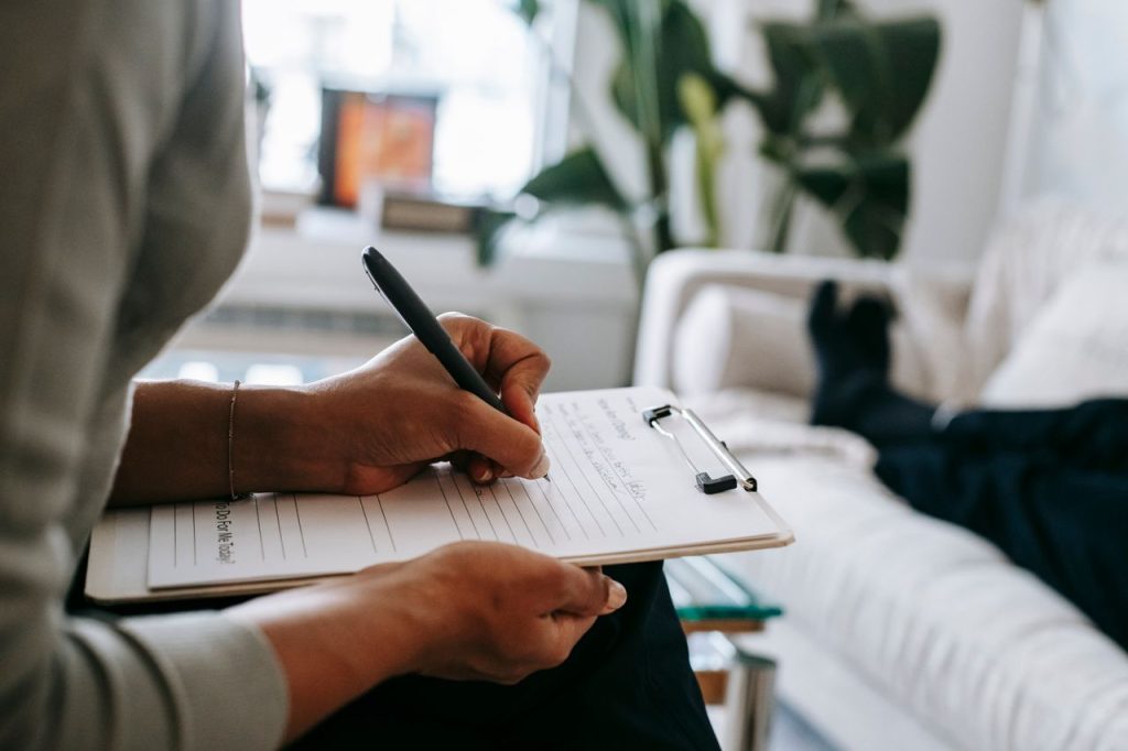 crop-ethnic-psychologist-writing-on-clipboard-during-session-5699456 Unrecognizable ethnic female therapist taking notes on clipboard while filling out form during psychological appointment with anonymous client lying on blurred background