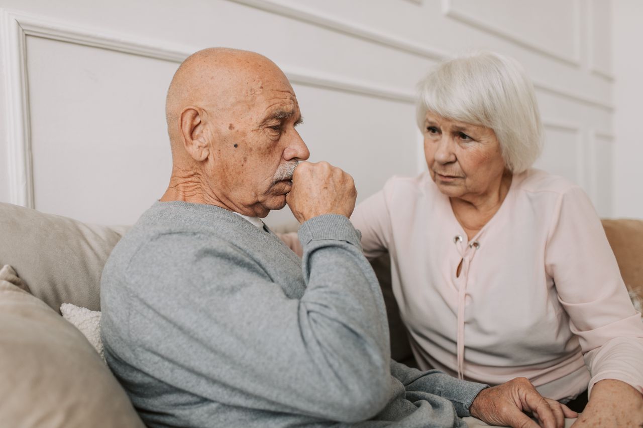 The Art of Drawing Readers In: Your attractive post title goes here An elderly couple sitting on a couch, showing care and affection indoors.